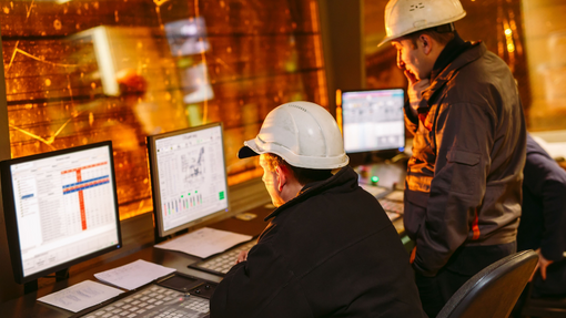 Engineers in hard hats looking at data on computer screens