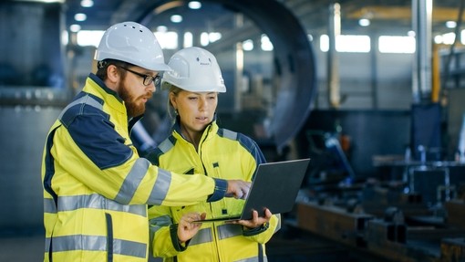 Two engineers in PPE looking at a laptop