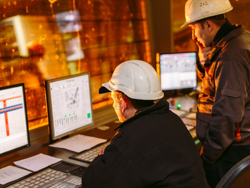 Engineers in hard hats looking at data on computer screens