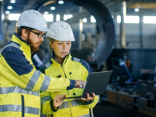 Two engineers in PPE looking at a laptop