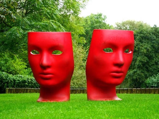 Sculpture of two red faces in a park