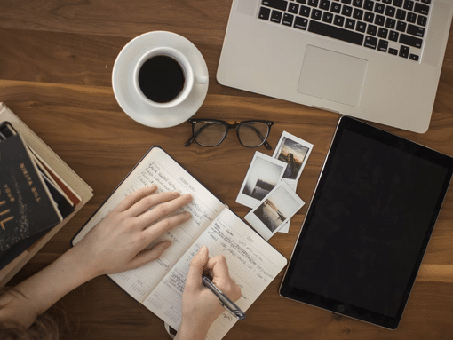 Desk with hands writing in notepad