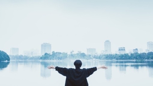 A person looking at a lake with their arms wide open