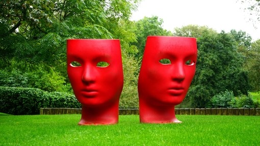 Sculpture of two red faces in a park