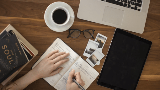 Desk with hands writing in notepad