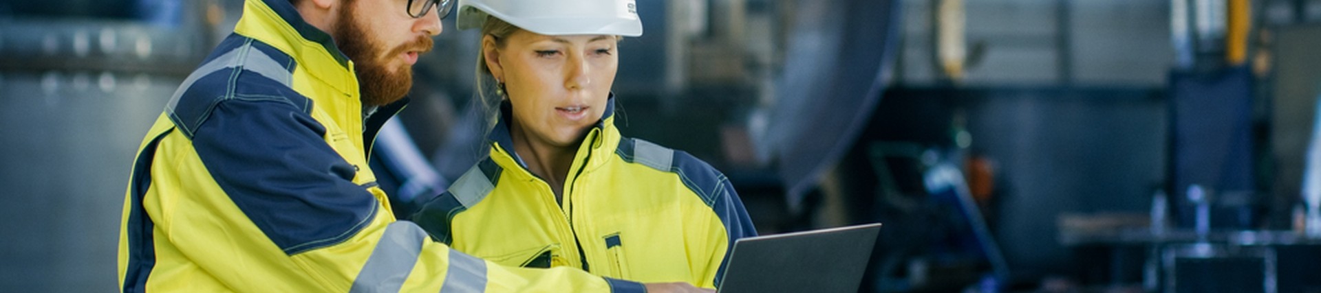 Two engineers in PPE looking at a laptop