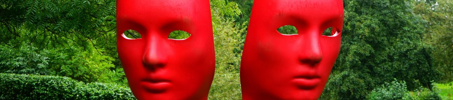 Sculpture of two red faces in a park